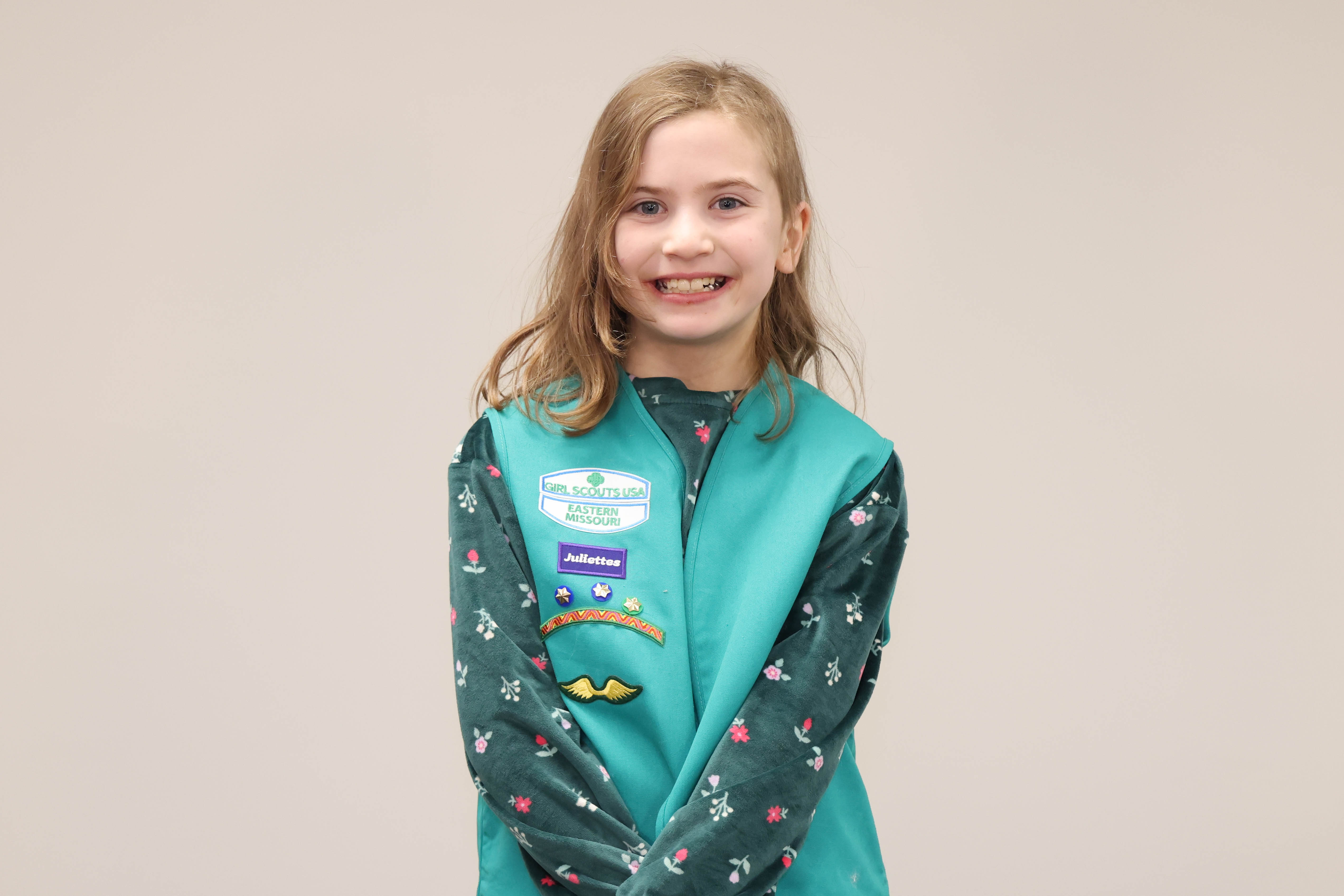 A young girl wearing a Girls Scouts shirt is shown at a recognition program.